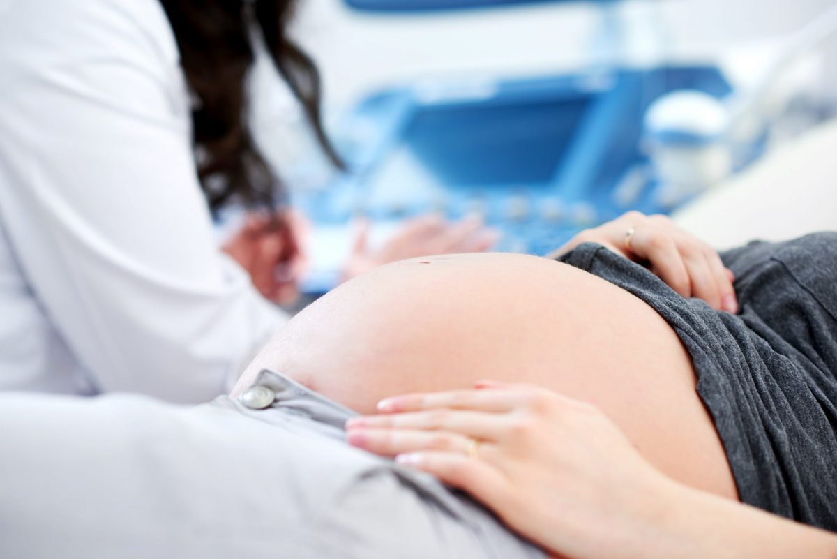 Przycięte zbliżenie kobiety w ciąży czekającej na lekarza, aby rozpocząć procedurę skanowania ultrasonograficznego w szpitalu przed cesarką
